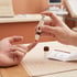 A person uses a lancing device to prick a finger for a blood sample next to a collection vial and instructions.