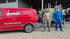 Roter Dreher Solar Heizung Kundendienst-Transporter neben zwei Männern und einem grünen Anhänger.