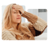 Blonde woman in sweater holding forehead, showing headache discomfort
