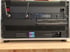 Ein schwarzes Tontechnik-Rack mit mehreren Geräten, Antennen und Beschriftungen wie „MLR“ und „ZoneMaster 2“.