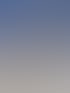 Ein orangefarbenes Comacchio-Bohrgerät auf Ketten steht auf einer verschneiten Fläche vor blauem Himmel.