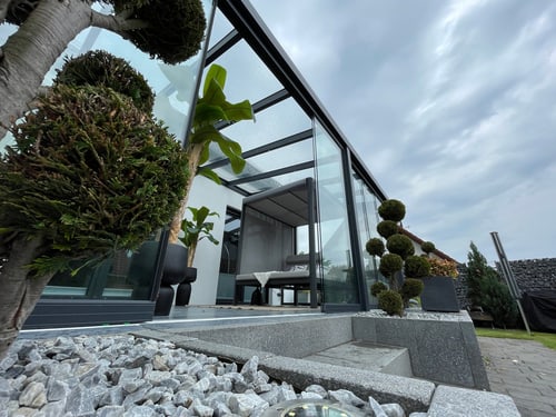 Glas-Terrassendach mit Lounge-Möbeln