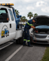 Towing Port Charlotte roadside assistance technician jump-starting a car battery beside a tow truck.