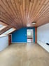 Leergeräumtes Dachgeschosszimmer mit Holzdecke, Dachfenstern und blauer Wand in Buchloe