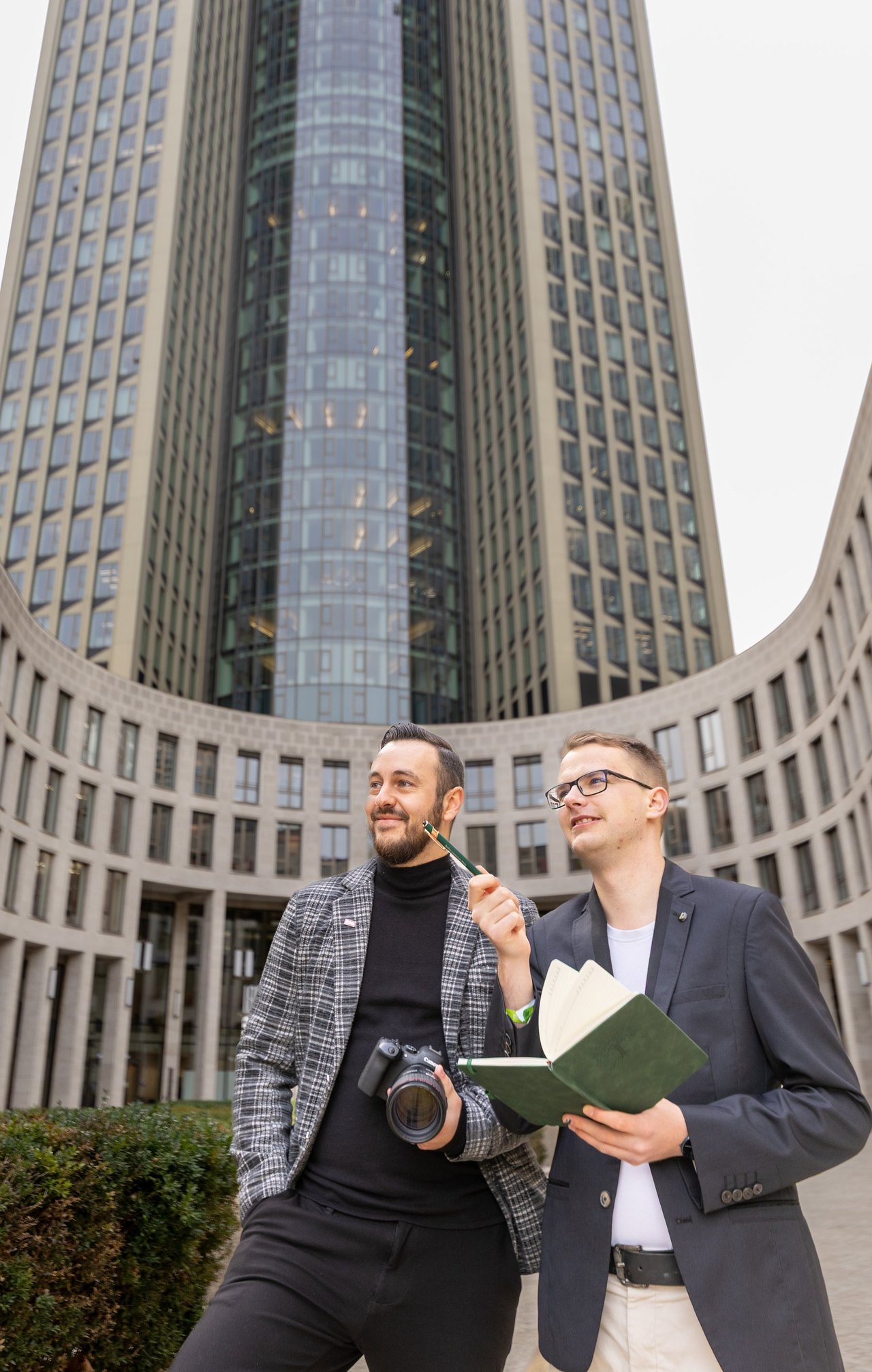 Lukas Wolf und Felix Mauersberger, Gründer von Visual Storytellers Leipzig, mit Kamera und Notizbuch vor einem Bürogebäude
