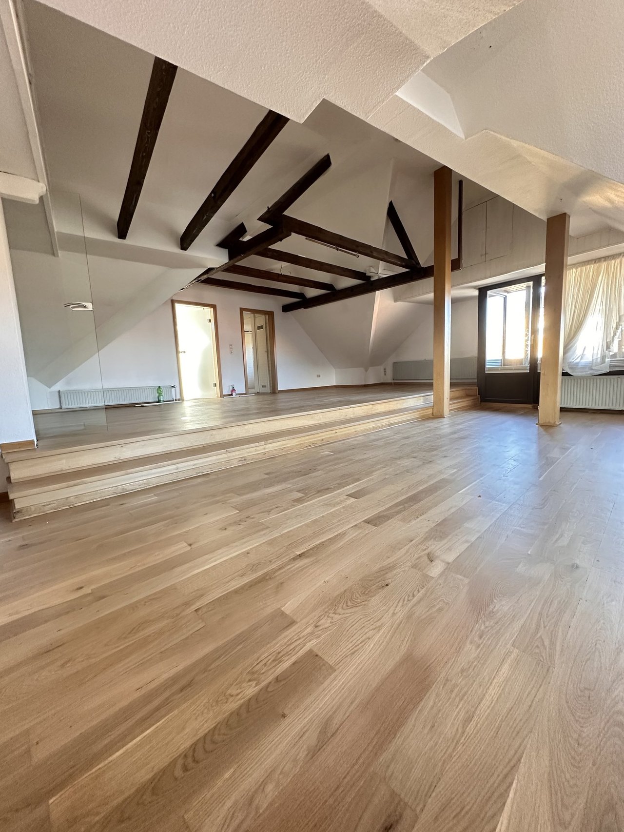 Wohnbereich der Dachgeschosswohnung mit Eichendielen und sichtbarem Gebälk