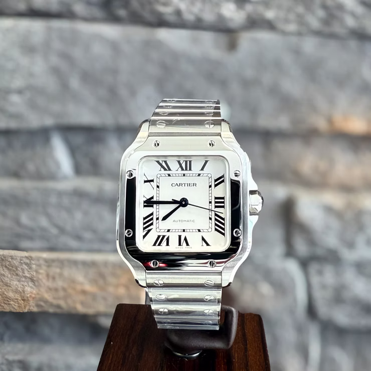 Silberne Cartier Santos Uhr auf Holzständer mit weißem Zifferblatt, schwarzen römischen Ziffern und "AUTOMATIC".