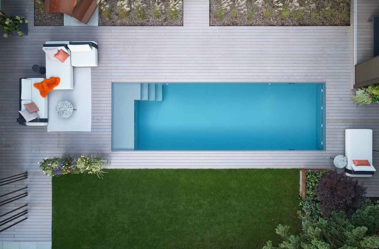 Rechteckiger Pool mit blauer Wasseroberfläche und Natursteinumrandung