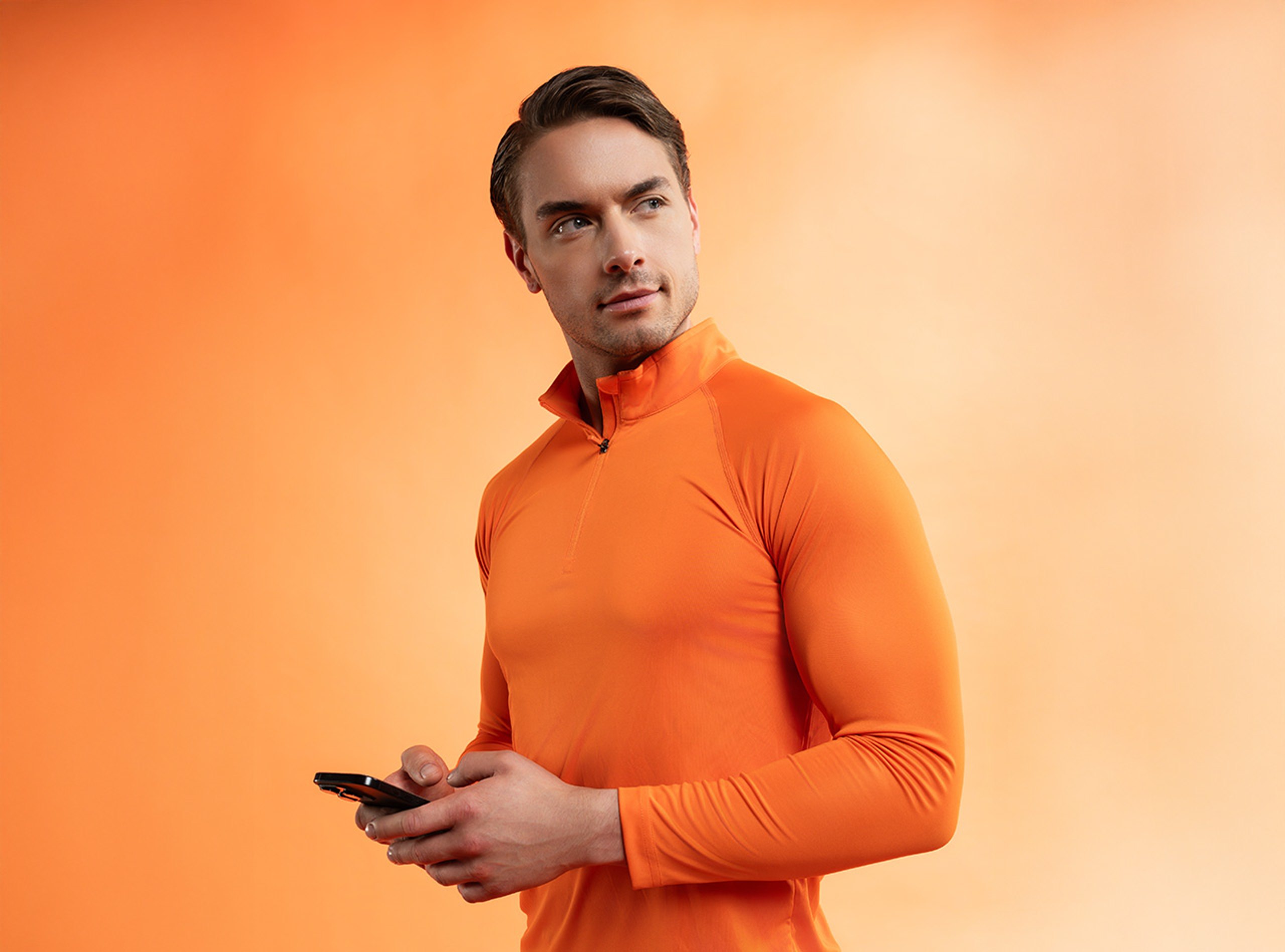 Mann in orangefarbener Sportkleidung mit Smartphone