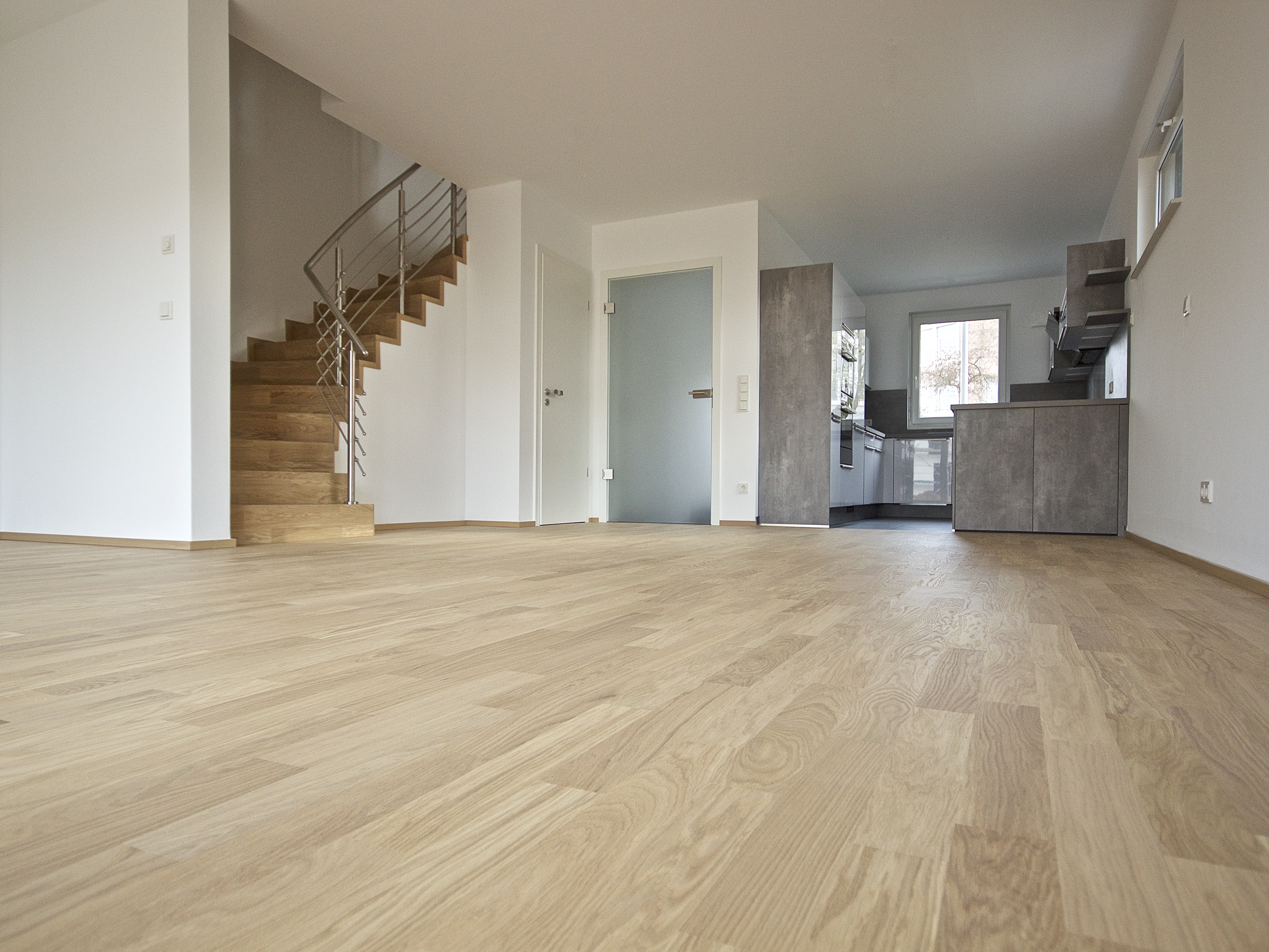 Wohnquartier Am Klosterpark – offener Wohnbereich mit Parkettboden, Küche und Holztreppe