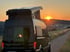 Aufstelldach Campervan bei Sonnenuntergang – Mercedes Sprinter mit geöffnetem Schlafdach am Feldweg