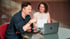 Markus Spenger sitzt mit einem Kunden beim Business-Coaching am Tisch mit MacBook