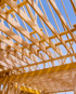 Holzbalken eines unfertigen Hausdachs vor blauem Himmel.