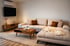 Modernes Wohnzimmer mit beigem Ecksofa, Holztisch, TV an der Wand und hellem Teppich.