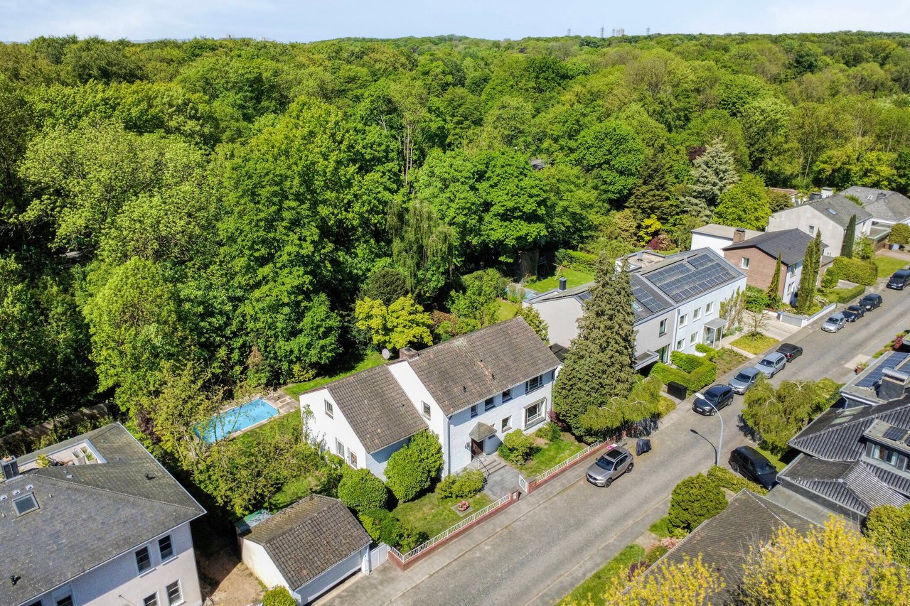 Luftbild: Haus mit Pool, dahinter der Stadtwald