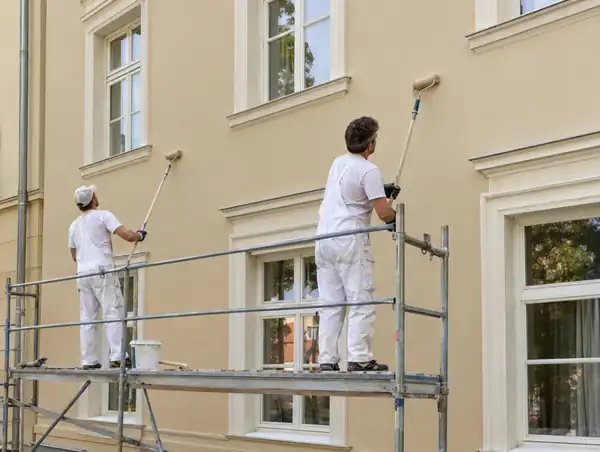 Maler streichen eine Altbaufassade vom Gerüst