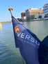 Blaue Versuro-Flagge weht vor dem Hafenbecken in Münster, im Hintergrund Bürogebäude am Wasser