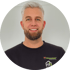 Ein lächelnder Mann mit Bart und grauem Haar trägt ein schwarzes T-Shirt mit "Schimmelwache" Logo.