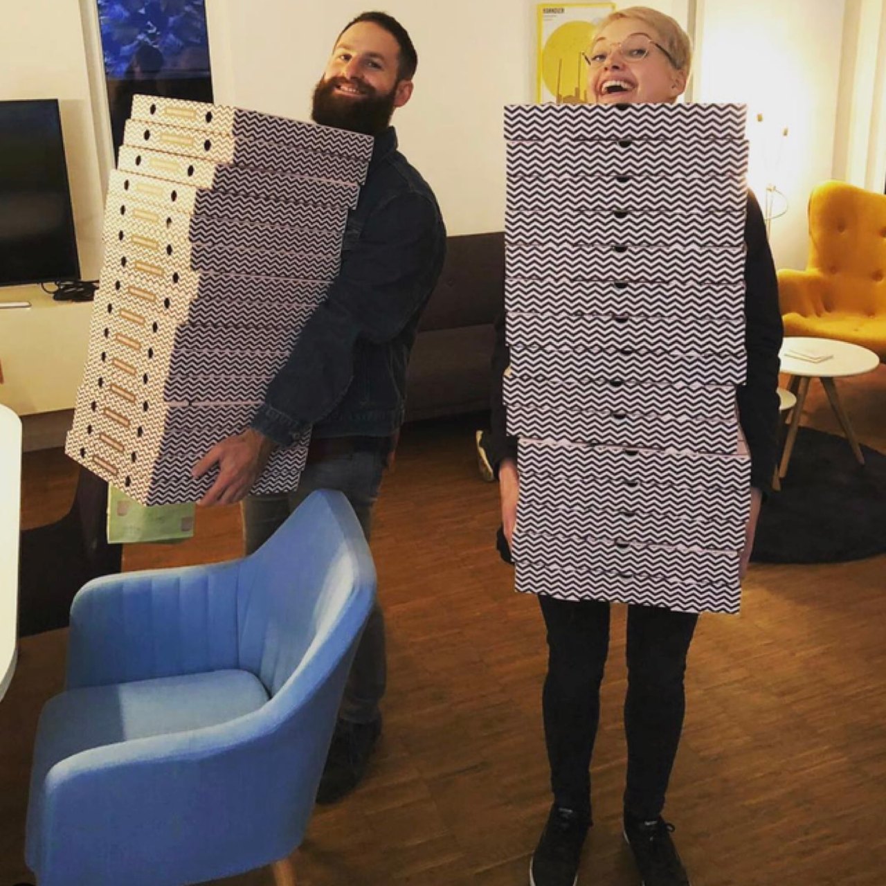 Zwei Teilnehmende tragen hohe Stapel Pizzakartons durch die NEOP Academy Hannover
