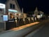 Beleuchtetes Restaurant "Chopin" mit Terrasse und Menütafel bei Nacht.