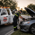 Towing Deltona roadside assistance technician providing a jump start to a disabled car with the hood open at sunset