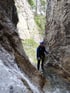 Eine Person in blauer Neoprenkleidung und Helm steht in einer felsigen Schlucht im Wasser.
