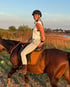 Laura Thater lächelnd auf ihrem Pferd in der Abendsonne