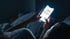 Eine Person liegt im dunklen Bett und hält ein hell leuchtendes Smartphone mit einer Textnachricht in den Händen.