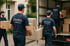 Vier Männer in blauen "ZENTRAL UMZÜGE"-T-Shirts tragen Möbel und Kartons zu einem Umzugswagen.