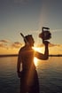 Silhouette einer Person mit Kamera-Rig vor der untergehenden Sonne