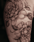 Großflächiges Tattoo mit detaillierten Pfingstrosen und Blättern in Schwarz-Grau-Schattierung auf der Haut.