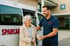 Ein Mann hilft einer älteren Frau aus einem SPARCAR-Transporter vor einem Krankenhaus.