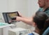 Zahnarzt zeigt einer Patientin eine digitale Gebissaufnahme auf einem Tablet in einer Zahnarztpraxis.