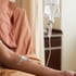 An intravenous IV drip bag hangs above a patient's arm with a catheter secured by medical tape.