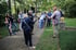Eine Gruppe von Menschen lauscht einem Mann, der auf einem Friedhof oder in einem Park spricht.