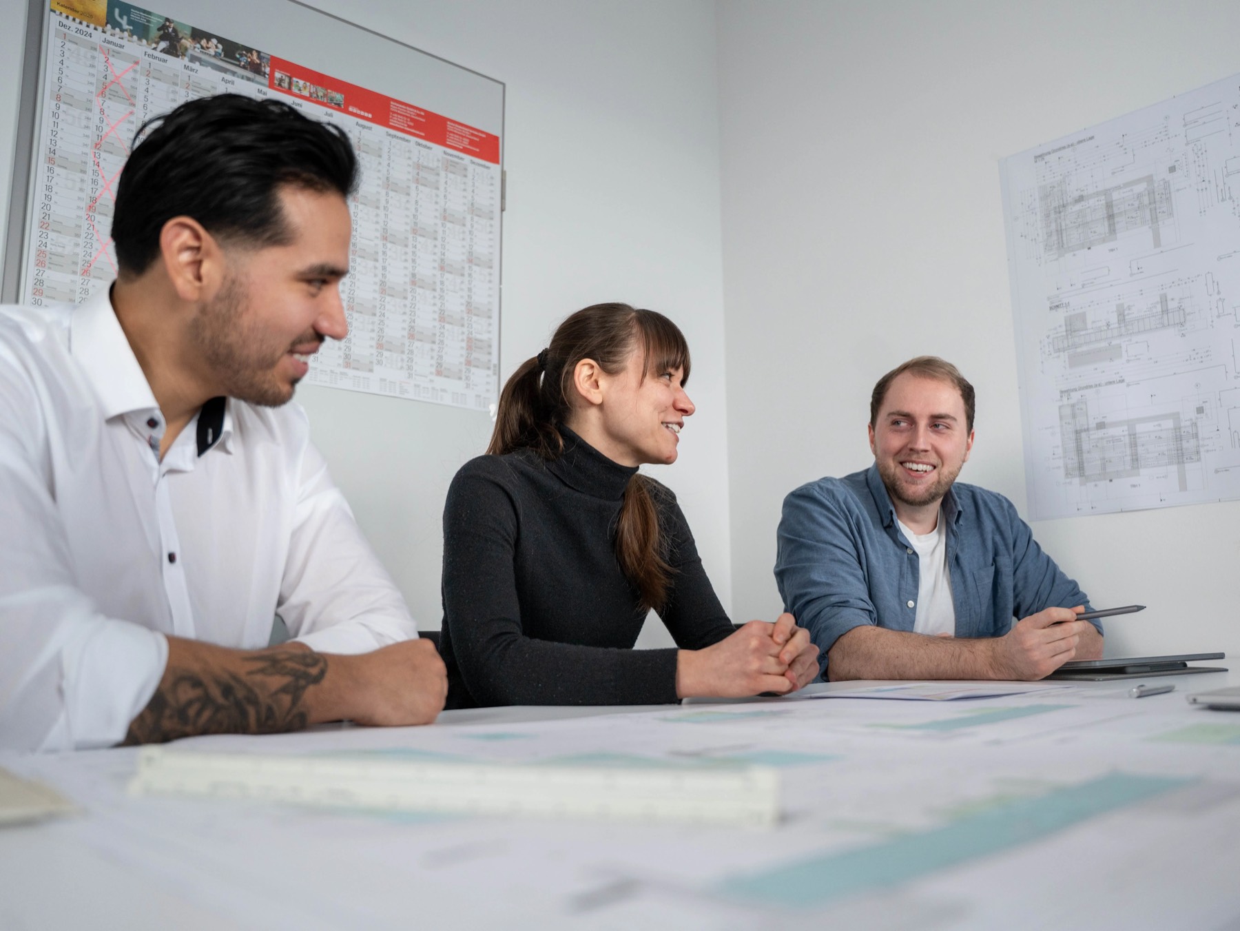 Drei Kollegen besprechen Pläne am Besprechungstisch