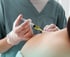 A person in scrubs injecting yellow liquid into the patient's shoulder for Peptide Therapy.