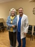 A woman and a doctor in a lab coat smiling.