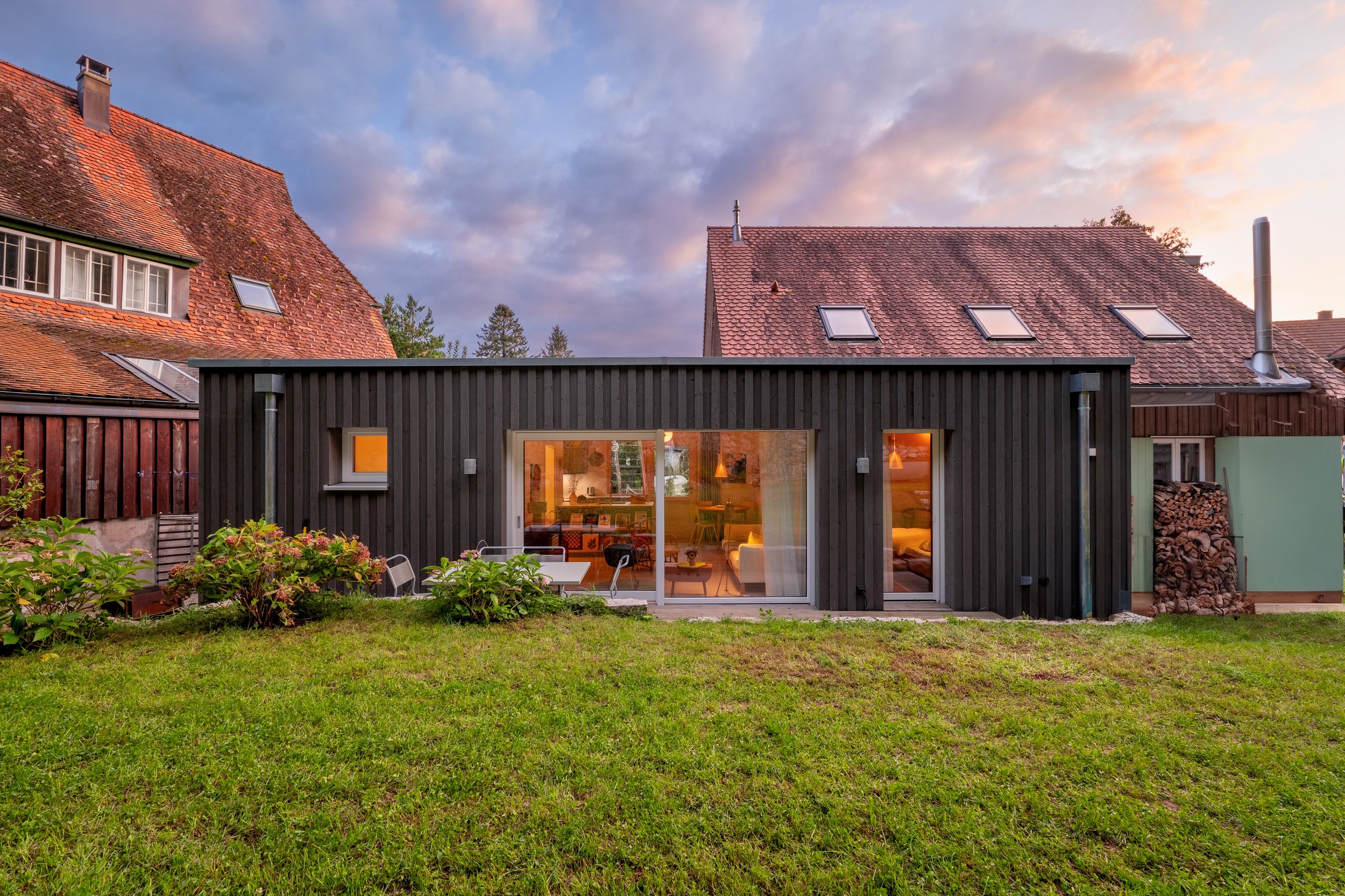 Das Holzhaus in der Abenddämmerung mit warm erleuchteten Fenstern