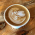 Latte Art in einer weißen Tasse auf einem Holztisch.