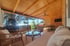 Geräumige überdachte Holzterrasse mit Hängesessel, Sofas, Couchtisch und Fernseher.