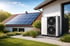 Wärmepumpe und Solarmodule auf dem Dach eines weißen Hauses mit Garten.