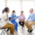 Doctor talking with three seated patients
