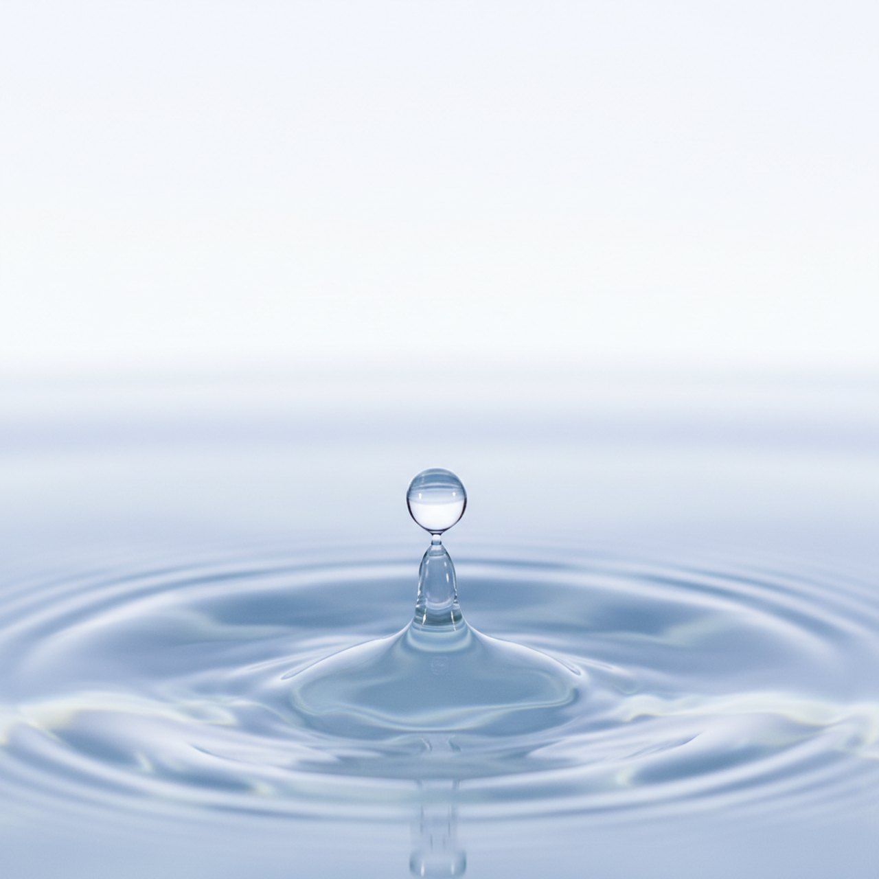 Wassertropfen, der feine Ringe auf einer stillen Wasseroberfläche erzeugt