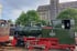 Dunkelgrüne Dampflokomotive mit roten Rädern und der Nummer 3, daneben ein brauner Waggon, dahinter ein Gebäude mit "RHENUS".