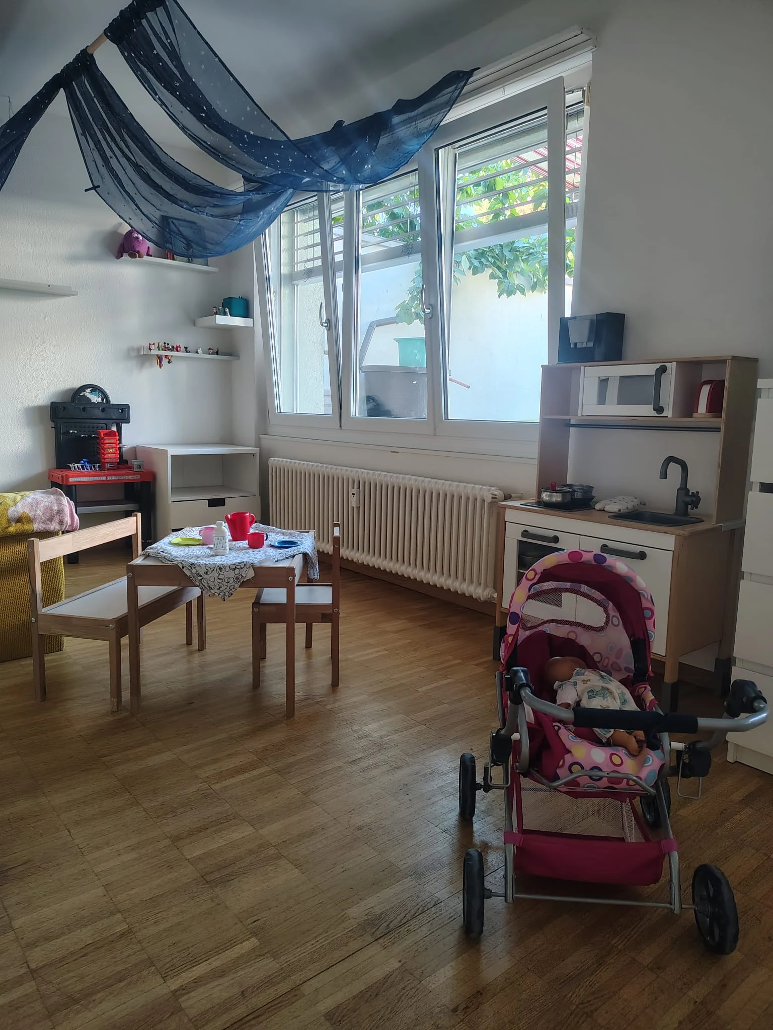 Bild 2: Spielzimmer mit Fenster, Spielküche und Kinderwagen.