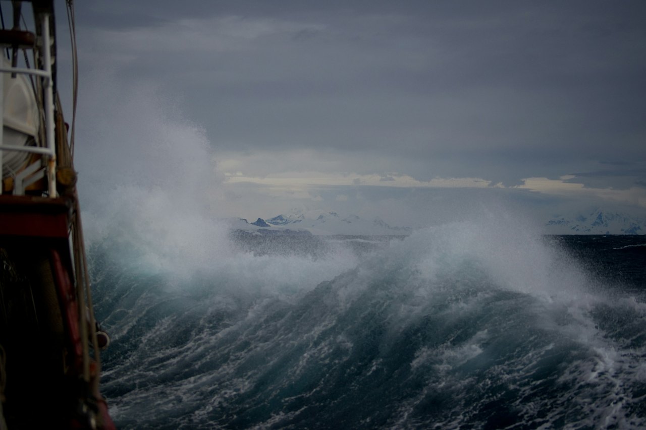 Eine große Welle bricht sich im grauen Meer und schäumt auf