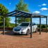 Silberner Opel Kombi parkt unter einem anthrazitfarbenen Carport mit transparentem Dach auf rotem Pflasterstein.