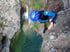 Person in Neoprenanzug und Helm schaut von einem Felsen auf einen Fluss hinunter.