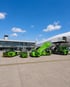 Förderung für elektrische Fahrzeuge und Systeme am Flughafen: mehrere grüne Elektro-Fahrzeuge für Bodenabfertigung und Vorfeldlogistik